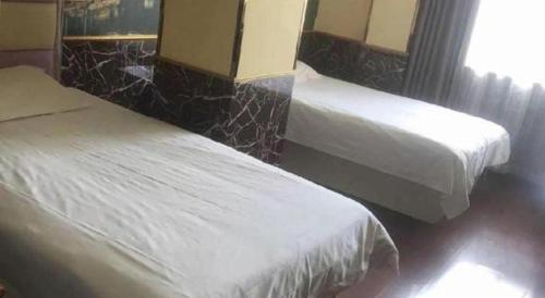 two beds in a hotel room with white sheets at Ease Hotel Shanghai Chuanhuan Nan Road Chuansha Metro Station in Shanghai