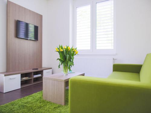 a living room with a green chair and a vase of yellow flowers at Villa Irene in Trenčianske Teplice