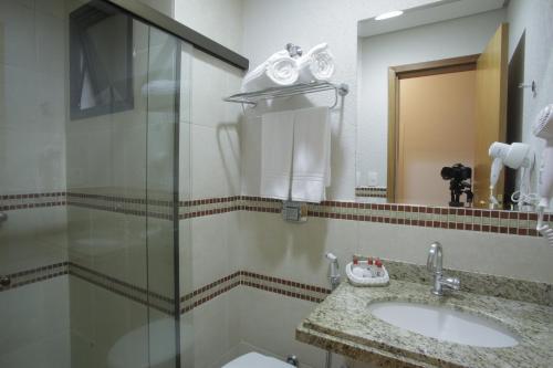 a bathroom with a sink, mirror, and bathtub at Castelo Inn Hotel in Goiânia
