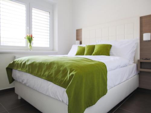 a white bedroom with a green blanket on a bed at Villa Irene in Trenčianske Teplice