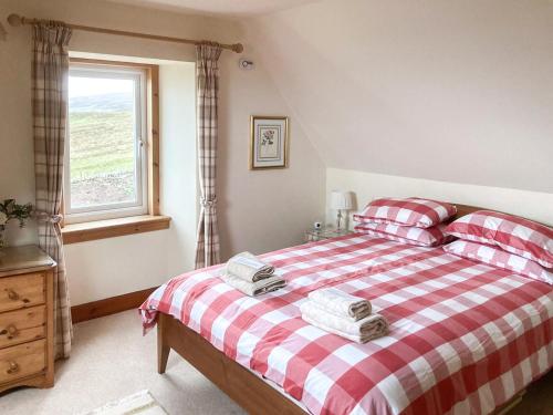 a bedroom with a red and white bed with a window at The Old School House in Lonbain