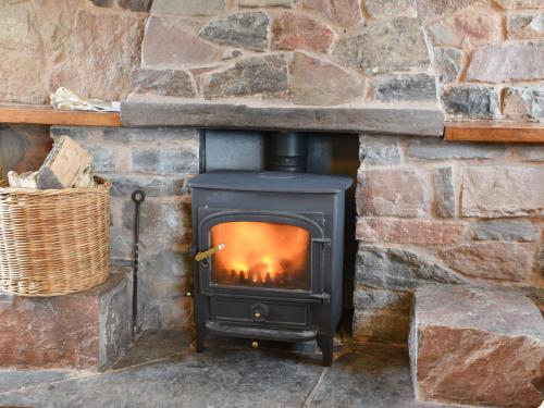 un poêle noir dans un mur de pierre dans l'établissement Keepers Cottage, à Garway