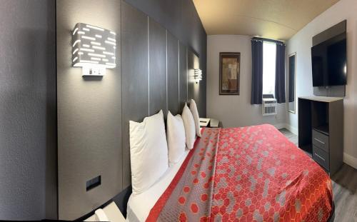 a hotel room with a bed with a red comforter at Blue Way Inn and Suites Roseville in Roseville