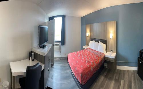 a small hotel room with a bed and a television at Blue Way Inn and Suites Roseville in Roseville