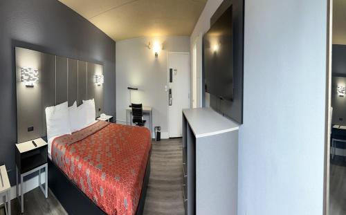 a hotel room with a bed and a flat screen tv at Blue Way Inn and Suites Roseville in Roseville