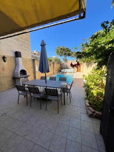 a patio with a table and chairs and an umbrella at Rustic Farmhouse with Pool in Xewkija