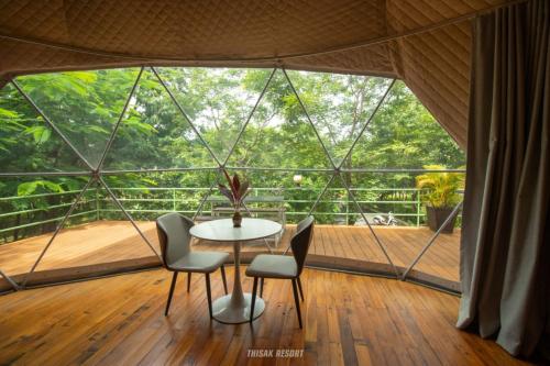 a room with a table and chairs and a large window at Thisak Resort Cheung phnom kulen in Siem Reap