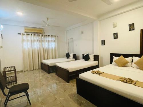 a hotel room with three beds and a chair at Sholay Villa in Galle