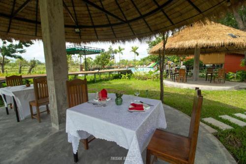 a table and chairs under an umbrella at a restaurant at Thisak Resort Cheung phnom kulen in Siem Reap