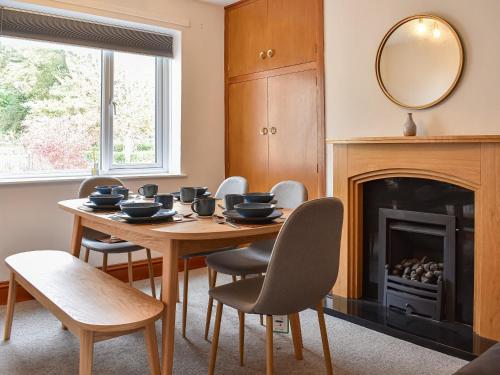 a dining room with a table and chairs and a fireplace at Tynedale in Keswick