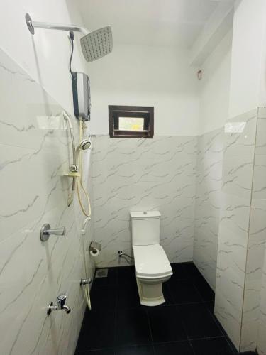 a white bathroom with a toilet and a shower at Sholay Villa in Galle