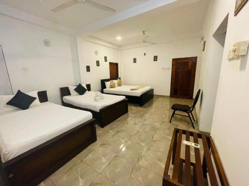 a room with two beds and a chair in it at Sholay Villa in Galle