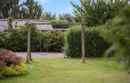 a swing set in a garden with bushes at Holiday Home Birkemose Ds Dnmk in Skovby