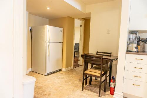 a kitchen with a refrigerator and a table and chairs at Bright & Spacious 2BR & Parking Near TTC & Shops in Toronto