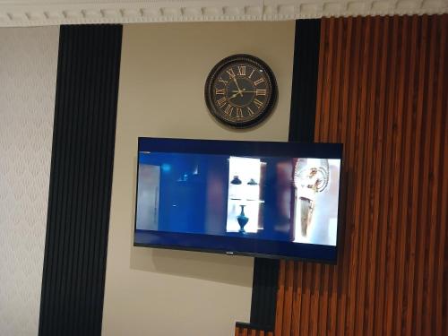 a clock on a wall next to a tv at Delux Studio apartment in Germiston