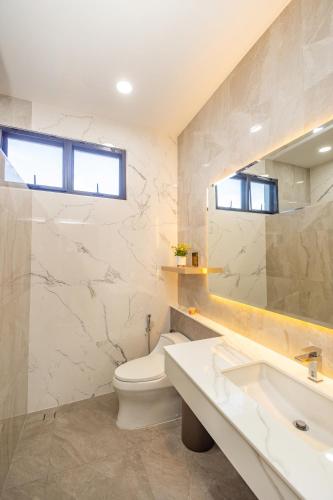 a bathroom with a toilet and a sink and a mirror at The Swan Pool Villa Hatyai เดอะสวอน พูลวิลล่าหาดใหญ่ in Ban Kohong