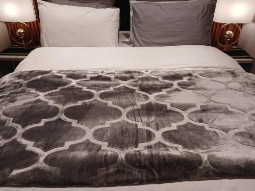 a bed with a black and white blanket on it at Delux Studio apartment in Germiston