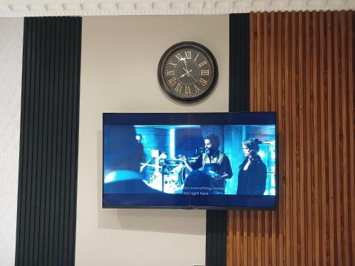 a tv with a clock on the wall and alevision at Delux Studio apartment in Germiston