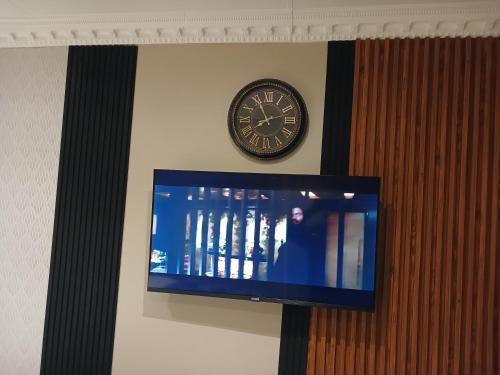 a clock on the wall next to a tv at Delux Studio apartment in Germiston