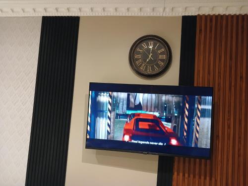 a clock and a tv with a car on a wall at Delux Studio apartment in Germiston
