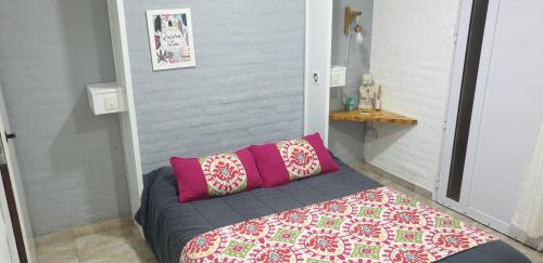 a bed with two pink pillows in a room at Minidpto in Tandil
