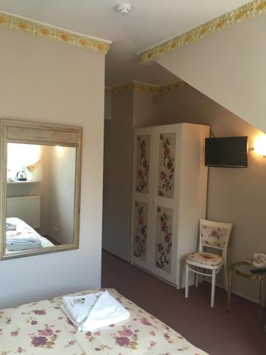 a bedroom with a bed and a mirror and a chair at Małopolanka & Spa in Krynica Zdrój