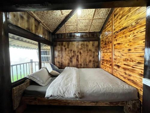 a bed in a room with a wooden wall at Sapa Guide Homestay & Trekking in Lao Cai