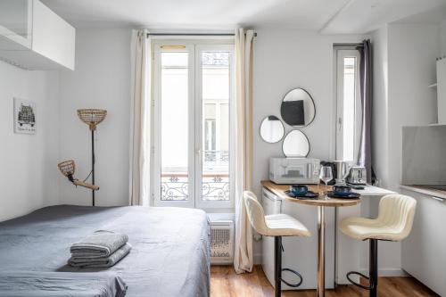 une chambre blanche avec un lit, une table et des chaises dans l'établissement Studio Daguerre - Montparnasse Paris 14th, à Paris
