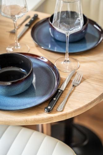 - une table en bois avec 2 assiettes bleues et des verres à vin dans l'établissement Studio Daguerre - Montparnasse Paris 14th, à Paris