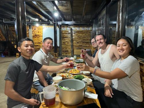 a group of people sitting around a table eating food at Sapa Guide Homestay & Trekking in Lao Cai