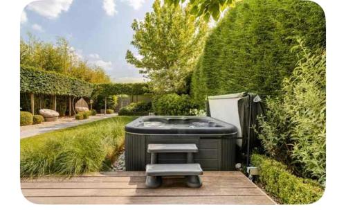 a hot tub sitting in the middle of a garden at La chambre du puits avec 2 jacuzzis , sauna et Hammam privatif in Tournai