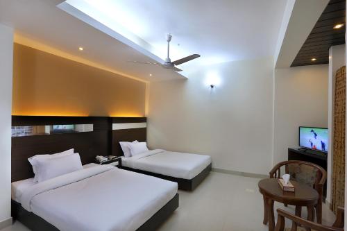 a hotel room with two beds and a flat screen tv at Hotel Holy Gate in Sylhet