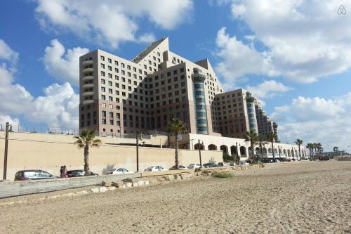 un grand bâtiment avec des voitures garées devant lui dans l'établissement Apartment on Haifa, à Haïfa