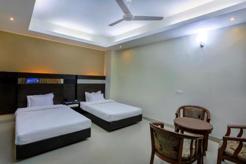 a hotel room with two beds and a table and chairs at Hotel Holy Gate in Sylhet