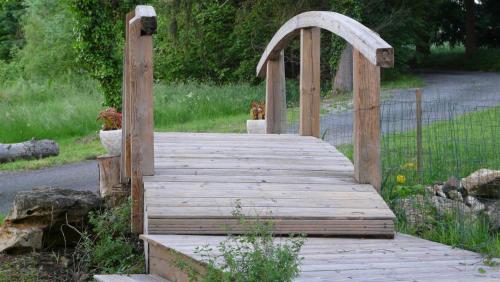 a wooden walkway with an arch in a garden at Domaine de Janis & Spa in Le Vigan