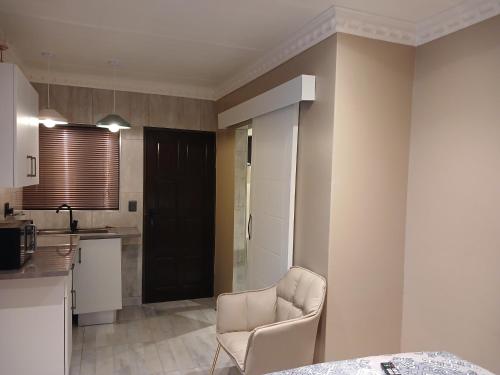 a living room with a chair and a kitchen at Delux Studio apartment in Germiston