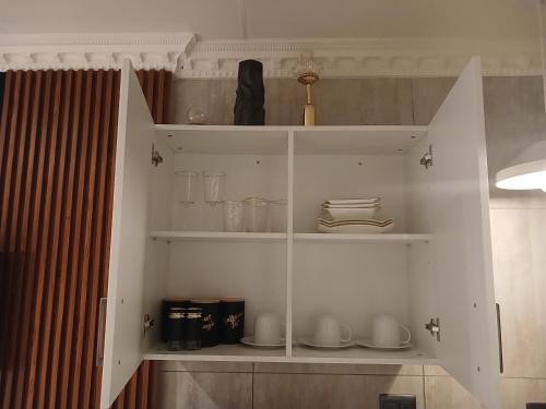 a white cabinet with cups and dishes on it at Delux Studio apartment in Germiston