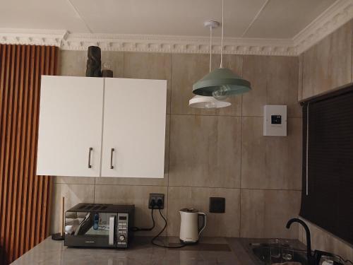 a kitchen with a white cabinet and a microwave at Delux Studio apartment in Germiston