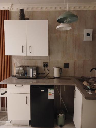 a kitchen with white cabinets and a black refrigerator at Delux Studio apartment in Germiston