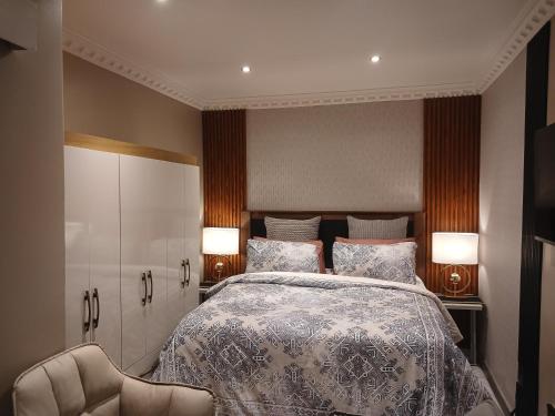 a bedroom with a bed with two lamps and a chair at Delux Studio apartment in Germiston