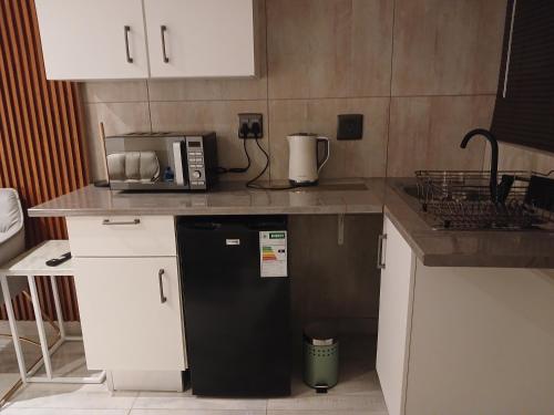 a kitchen with a black refrigerator and white cabinets at Delux Studio apartment in Germiston