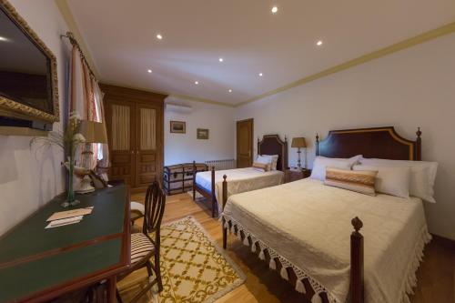 ein Hotelzimmer mit 2 Betten, einem Schreibtisch und einem Bett in der Unterkunft Casa de São Domingos in Peso da Régua