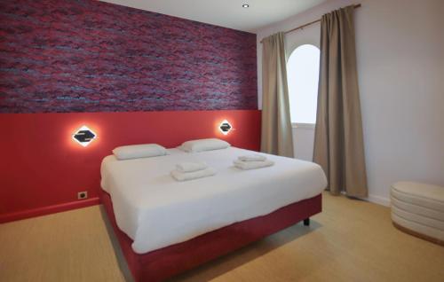 a bedroom with a large bed with a red wall at Villa Des Artistes in Suze-la-Rousse