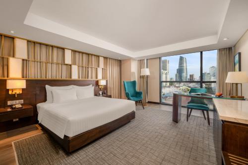 a bedroom with a bed and a desk and a window at New Orient Hotel Da Nang in Da Nang