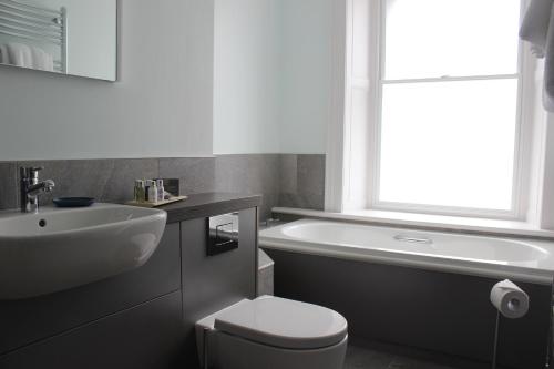 a white toilet sitting next to a bath tub at The Tilman in Barmouth