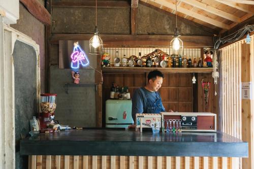 a woman standing behind a counter in a kitchen at MEKIKI古民家 in Yamanashi