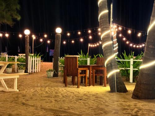 a table and chairs on a beach with lights at Hotel Coral Bay in Trincomalee
