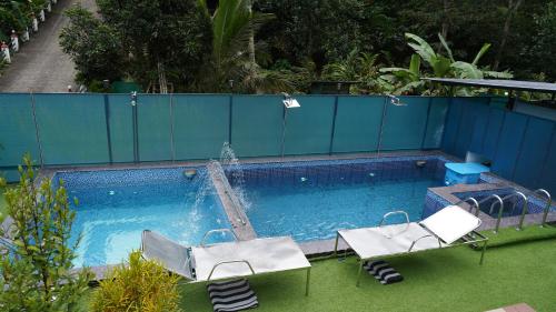 a swimming pool with two chairs and a fountain at Arabian Nights Munnar Pool Villa in Munnar