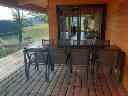 une terrasse en bois avec une table et des chaises sur une maison dans l'établissement Le coin de paradis du Haut-Jura, à Entre-Deux-Monts