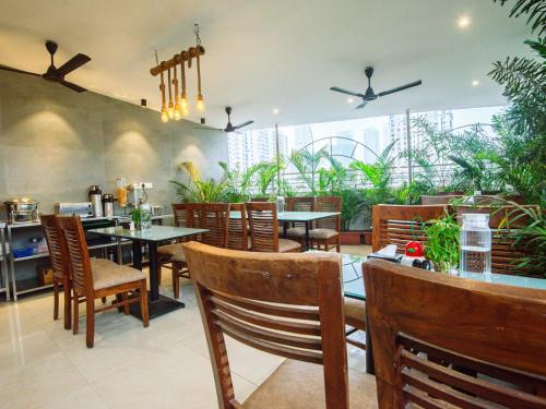 a restaurant with tables and chairs and plants at Hotel Skylink Hospitality Mahalaxmi in Mumbai
